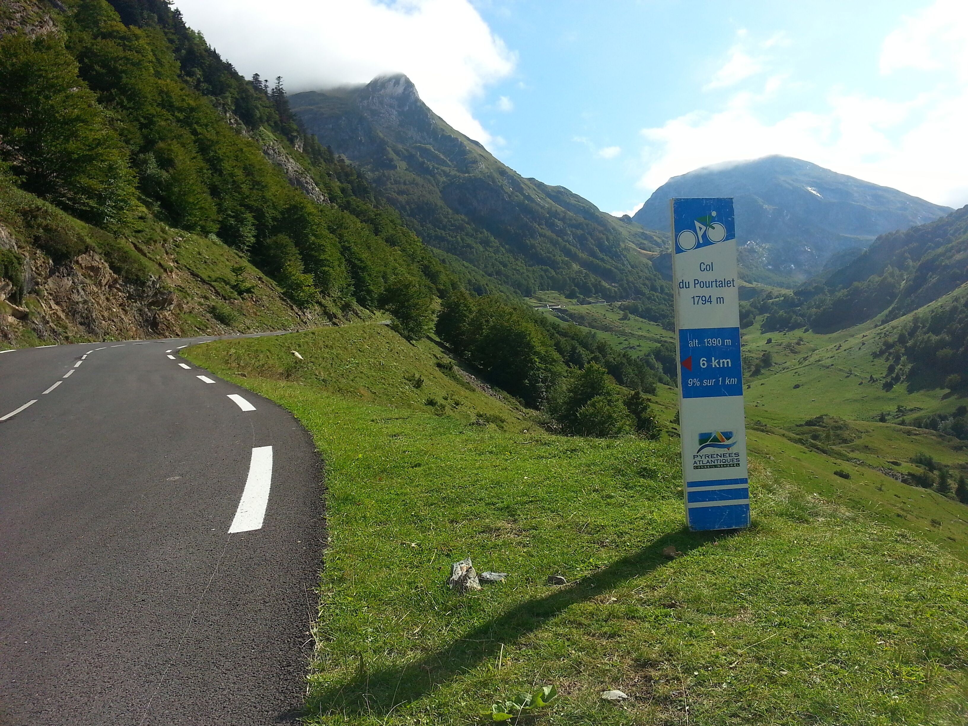 A winding road in a mountainous area with a sign indicating the Col du Portalet at 1794 meters altitude.