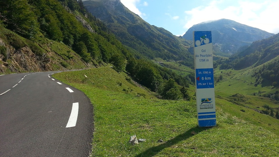 A winding road in a mountainous area with a sign indicating the Col du Portalet at 1794 meters altitude.