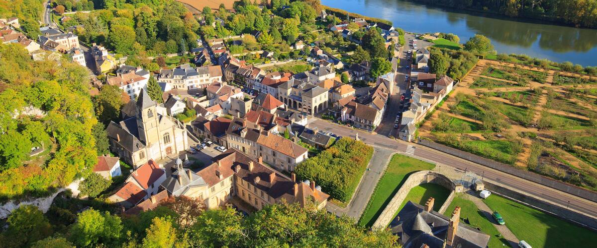 A riverside town with historic buildings, a church, and surrounding greenery.