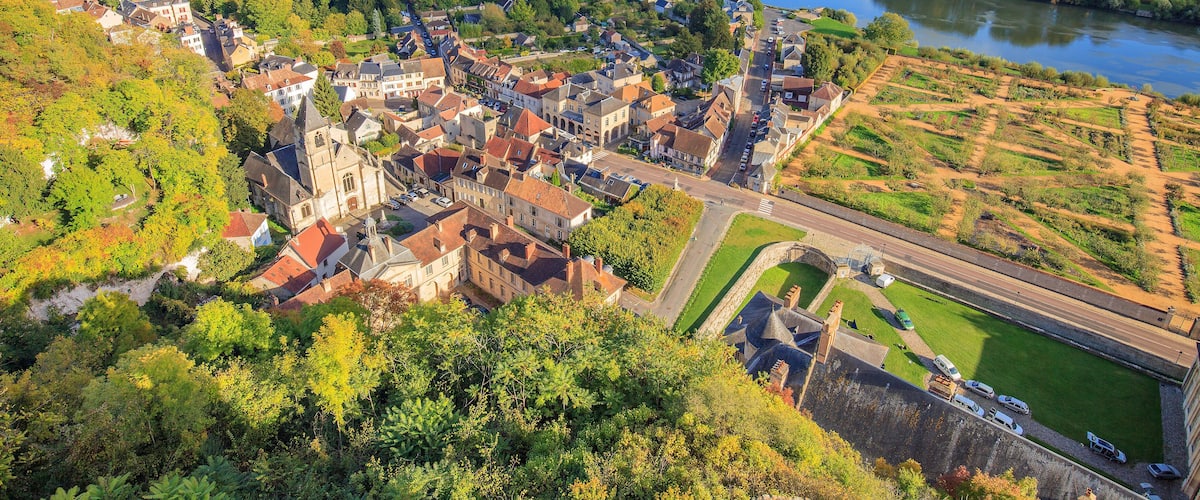 A town nestled by a river with a prominent church and surrounding greenery.