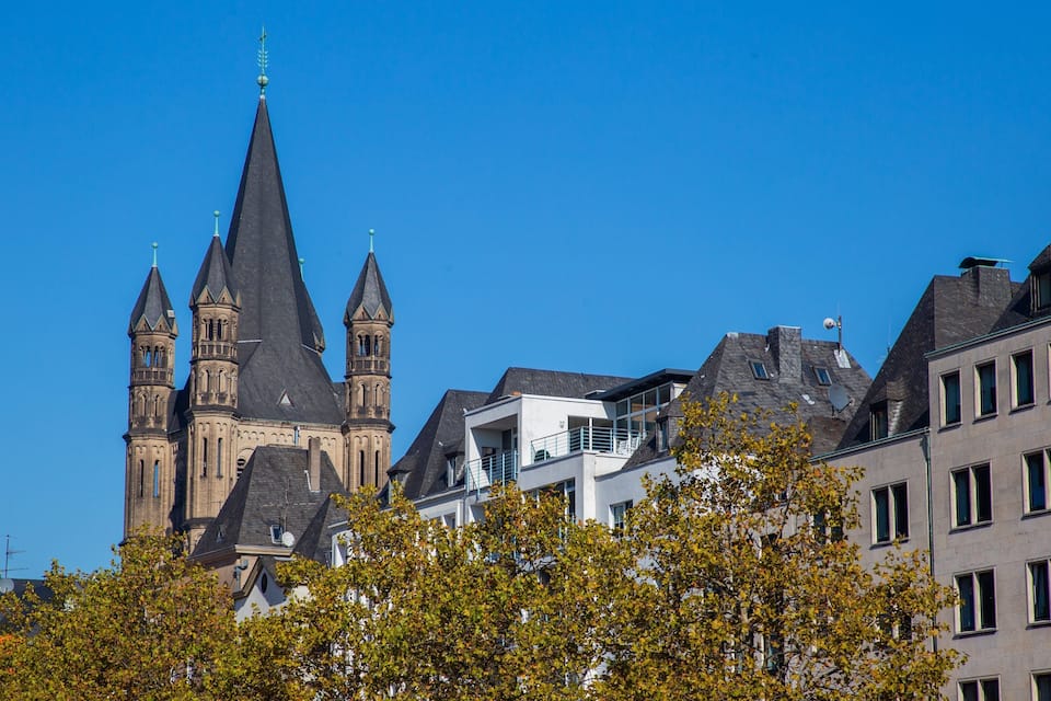 Une église historique dotée d’un clocher imposant et un bâtiment moderne agrémenté de balcons.