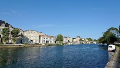 A calm river with buildings and a bridge in the background.