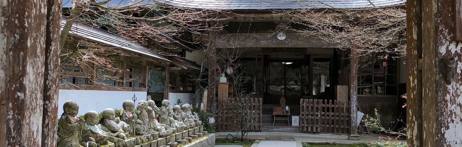 Um edifício japonês tradicional com telhado telhado e estátuas de pedra ao longo do caminho.