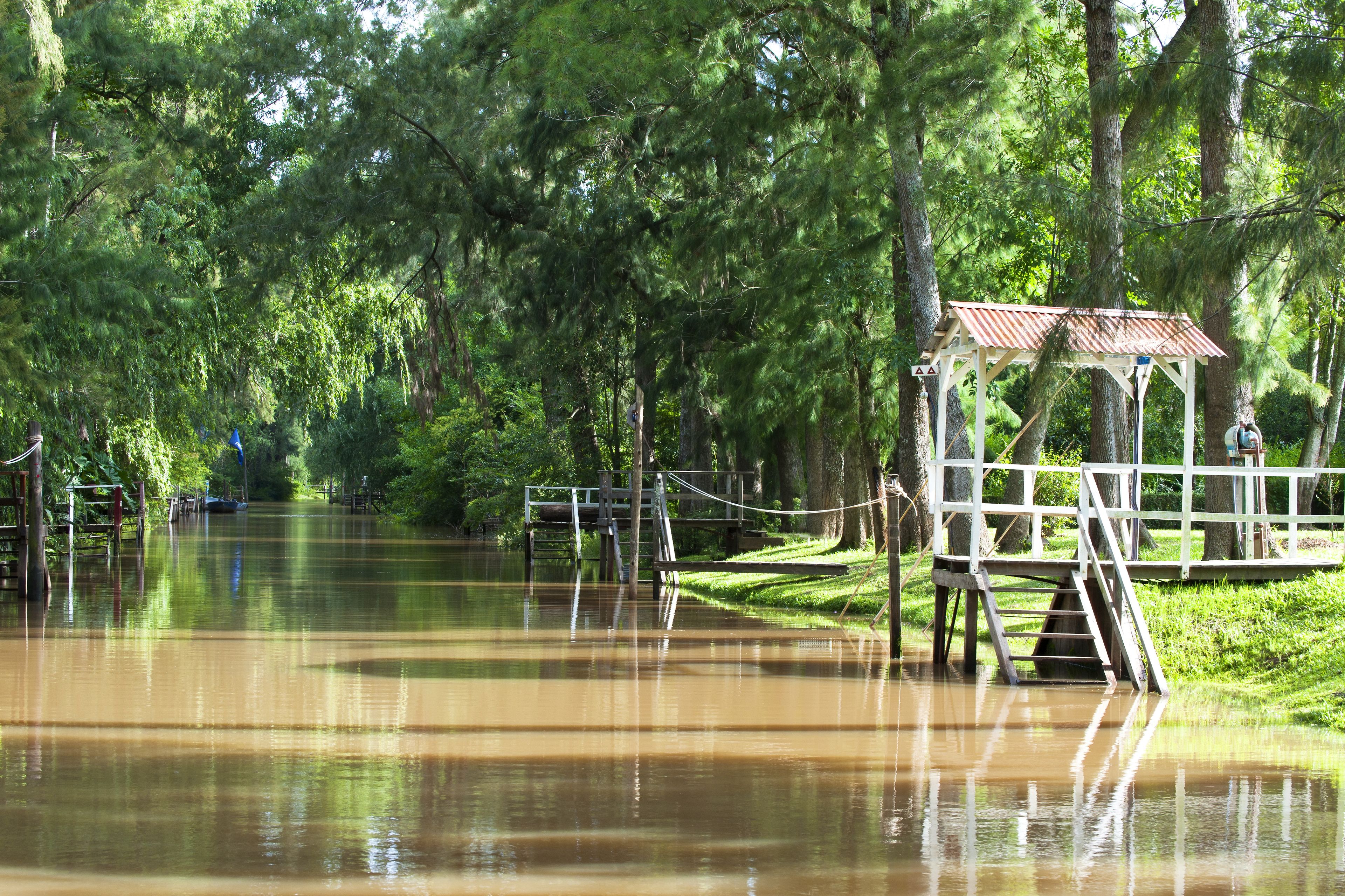 A flooded park with a wooden gazebo and a bridge.