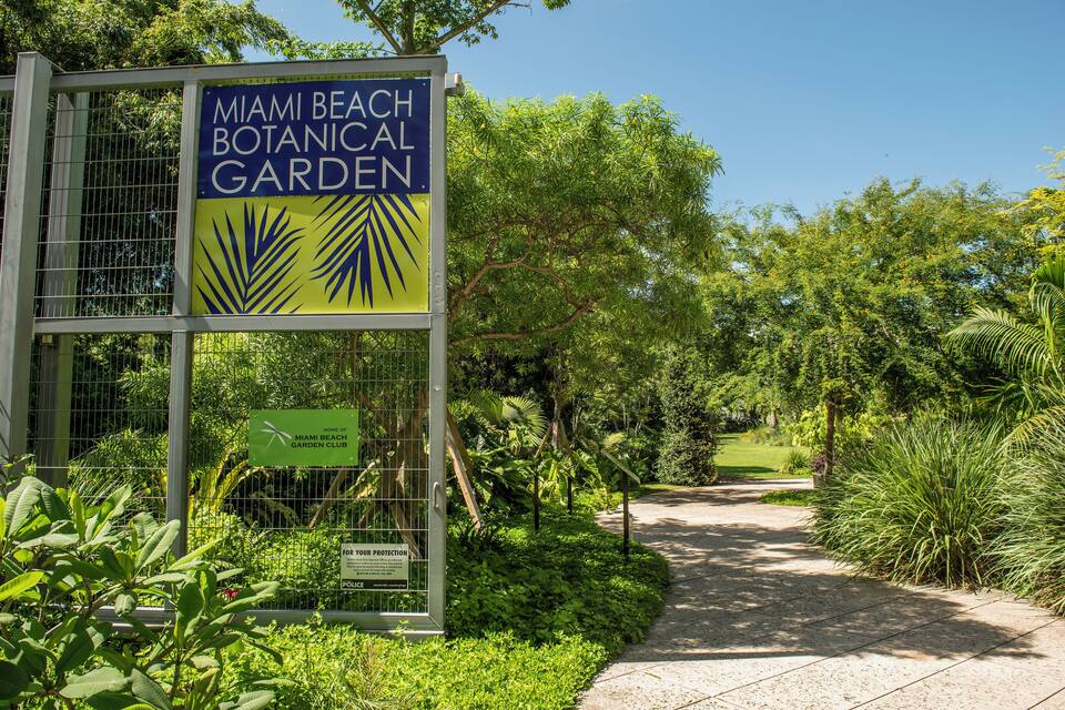 Placa para o Jardim Botânico de Miami Beach, com um caminho e vegetação exuberante.