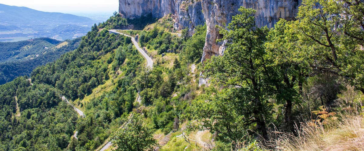 A mountainous landscape with a prominent cliff and winding roads.