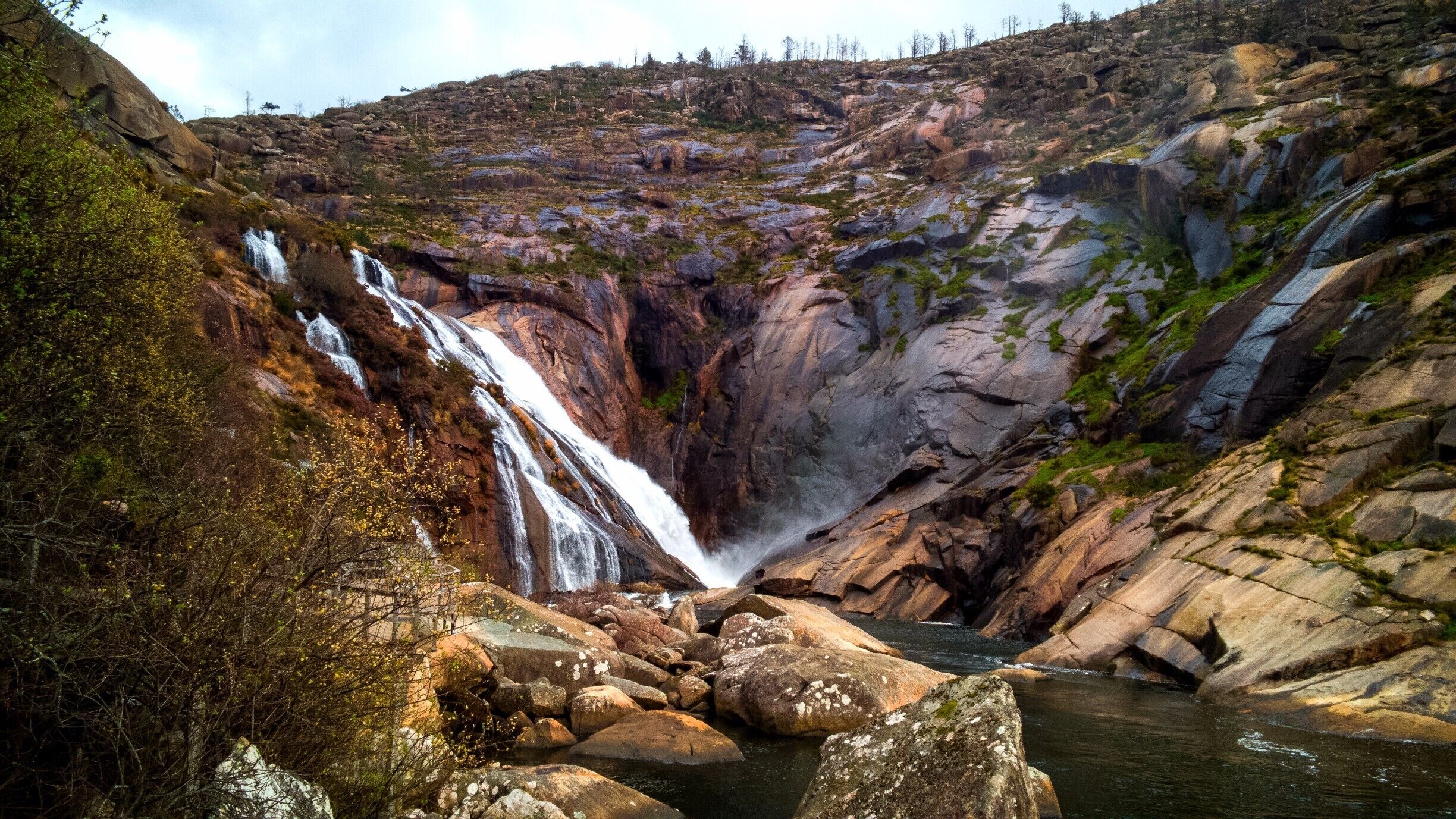 A waterfall cascading down a rocky cliff into a river.