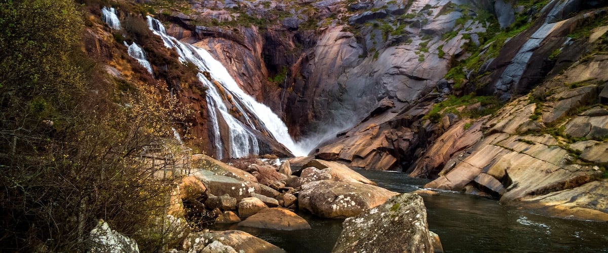 A waterfall cascading down a rocky cliff into a river.