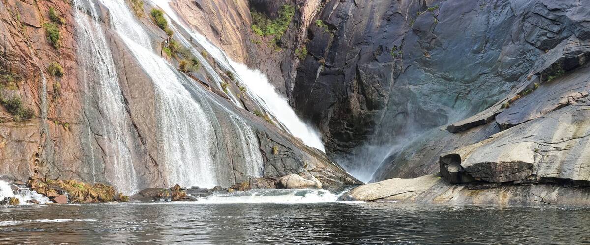A waterfall cascading down a rocky cliff into a river.