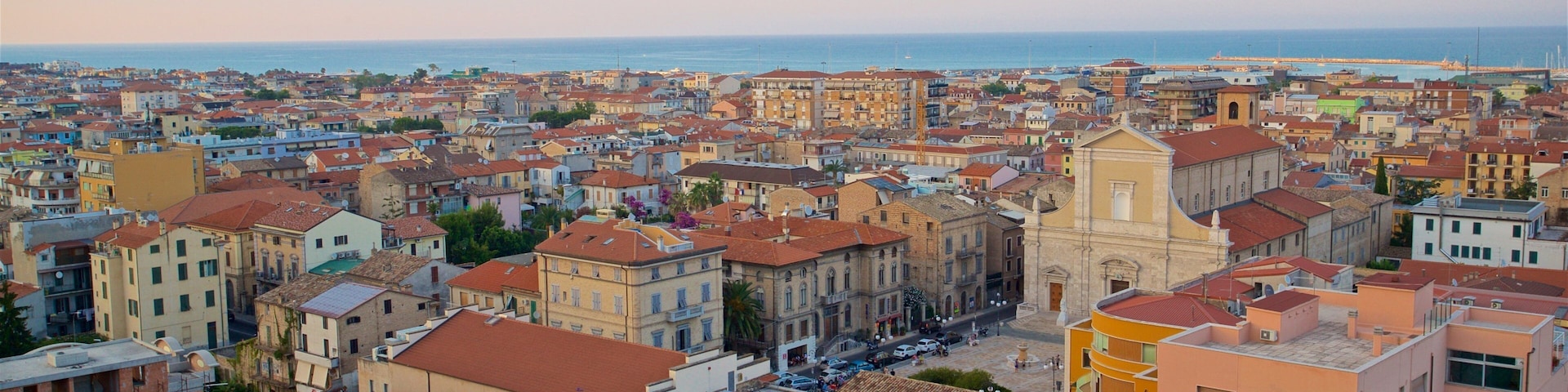 Un paisaje urbano costero con edificios históricos, una iglesia destacada y una vista despejada del mar.