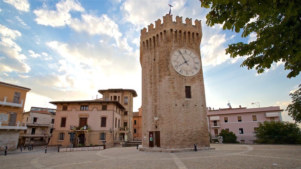 A historic tower with a clock, surrounded by traditional buildings and cobblestone streets.