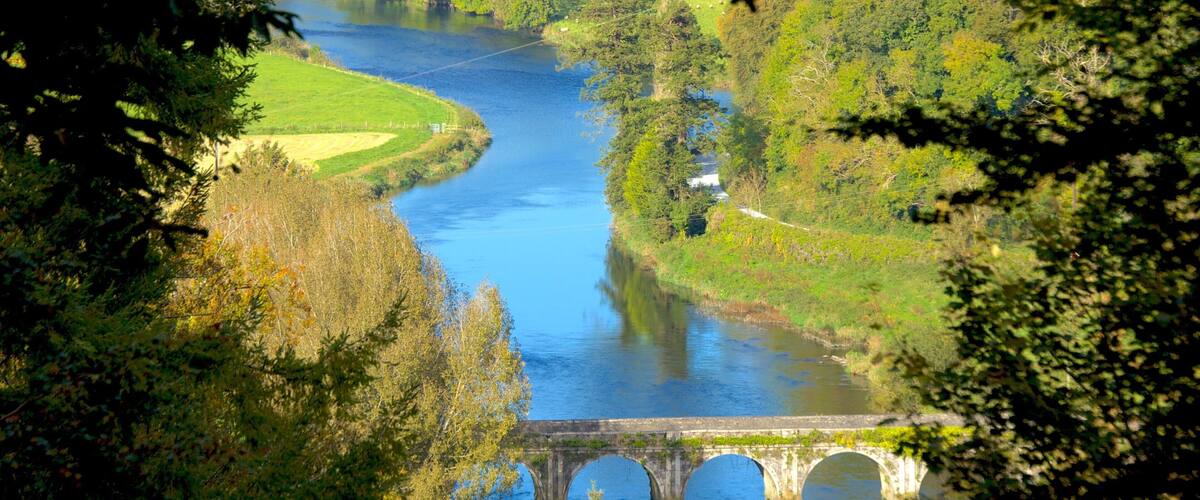 A river flowing through a valley with a stone bridge.