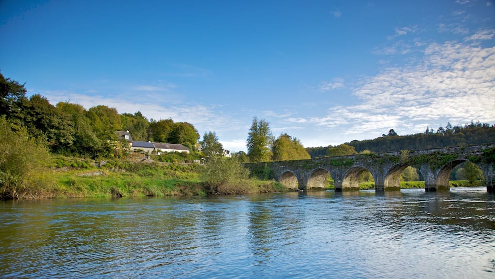 Eine Stebrücke über einem Fluss, am linken Ufer befinden sich Häuser.