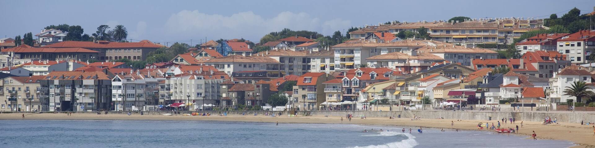 A coastal town with buildings along the beach and waves crashing onto the shore.