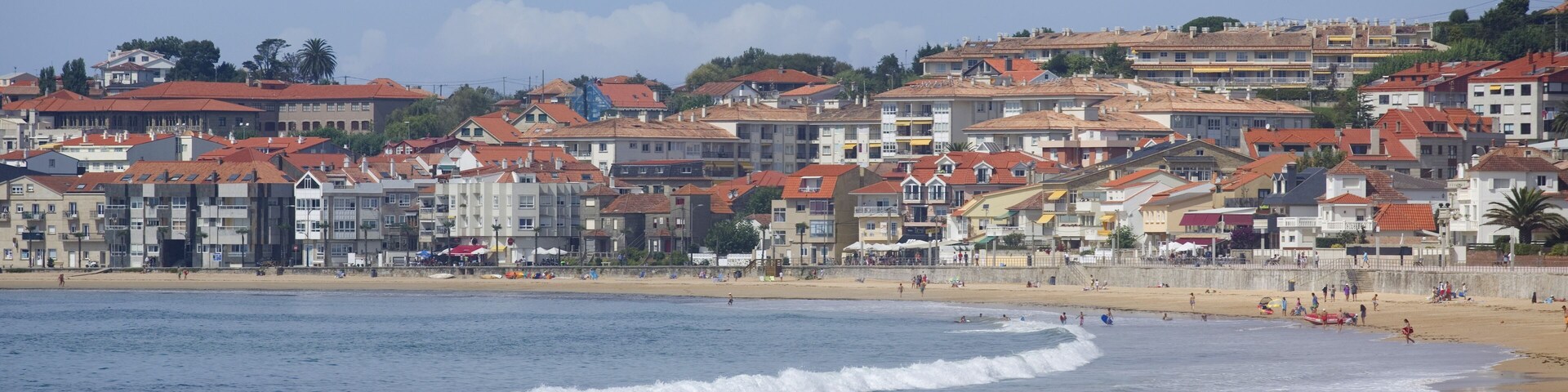 Eine Küstenstadt mit Gebäuden entlang des Strandes und brechenden Wellen.