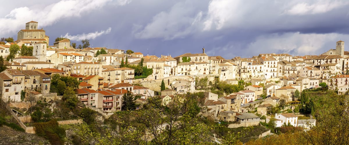 A hillside town with historic buildings, a prominent church tower, and lush greenery.