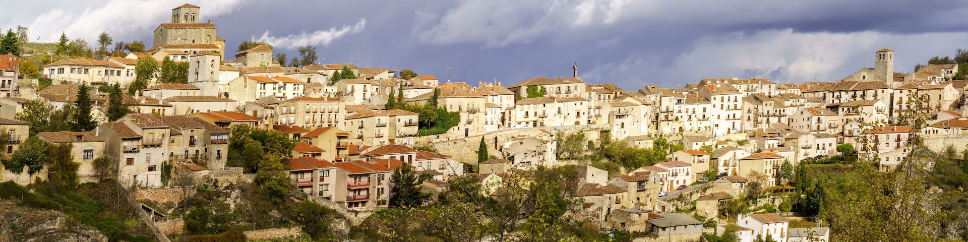 A hillside town with historic buildings, a prominent church tower, and lush greenery.