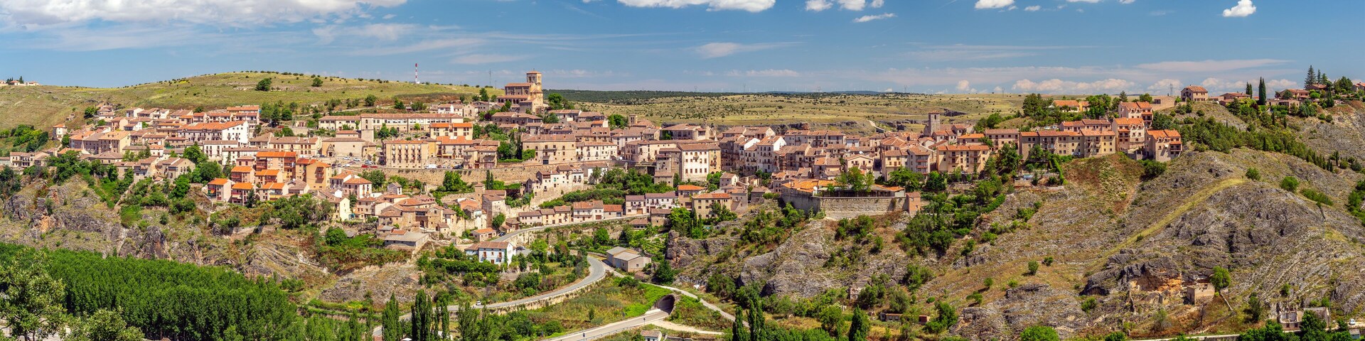 Un pueblo histórico ubicado en un valle con edificios escalonados y una torre destacada.