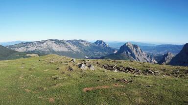 A mountainous landscape with rocky outcrops and grassy areas under a clear blue sky.