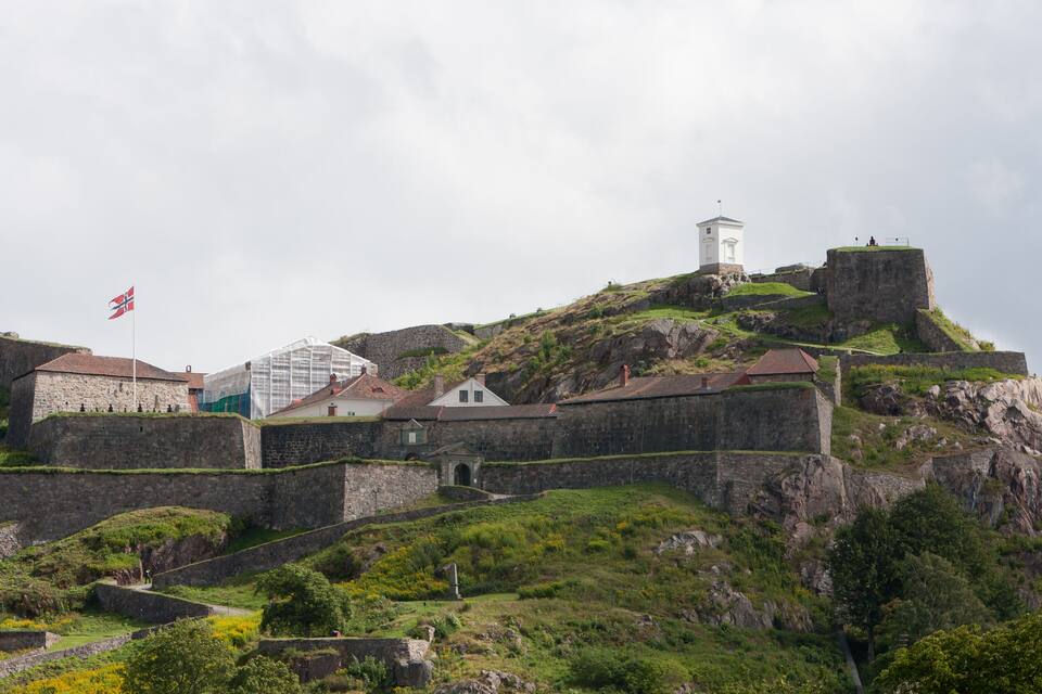 A historic fortification with stone walls and a lighthouse on a hill.