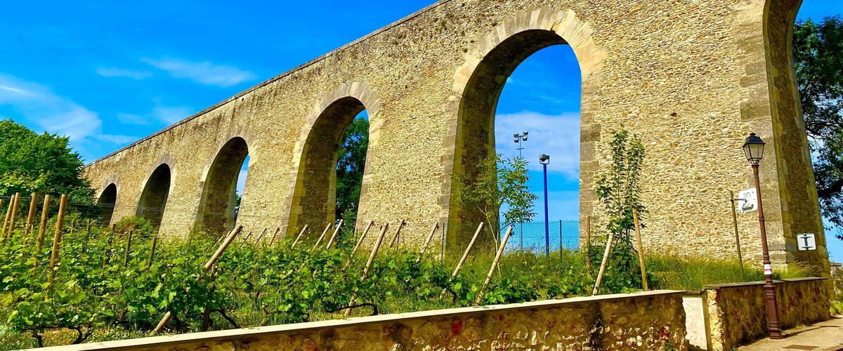 A stone aqueduct with multiple arches under a clear blue sky.