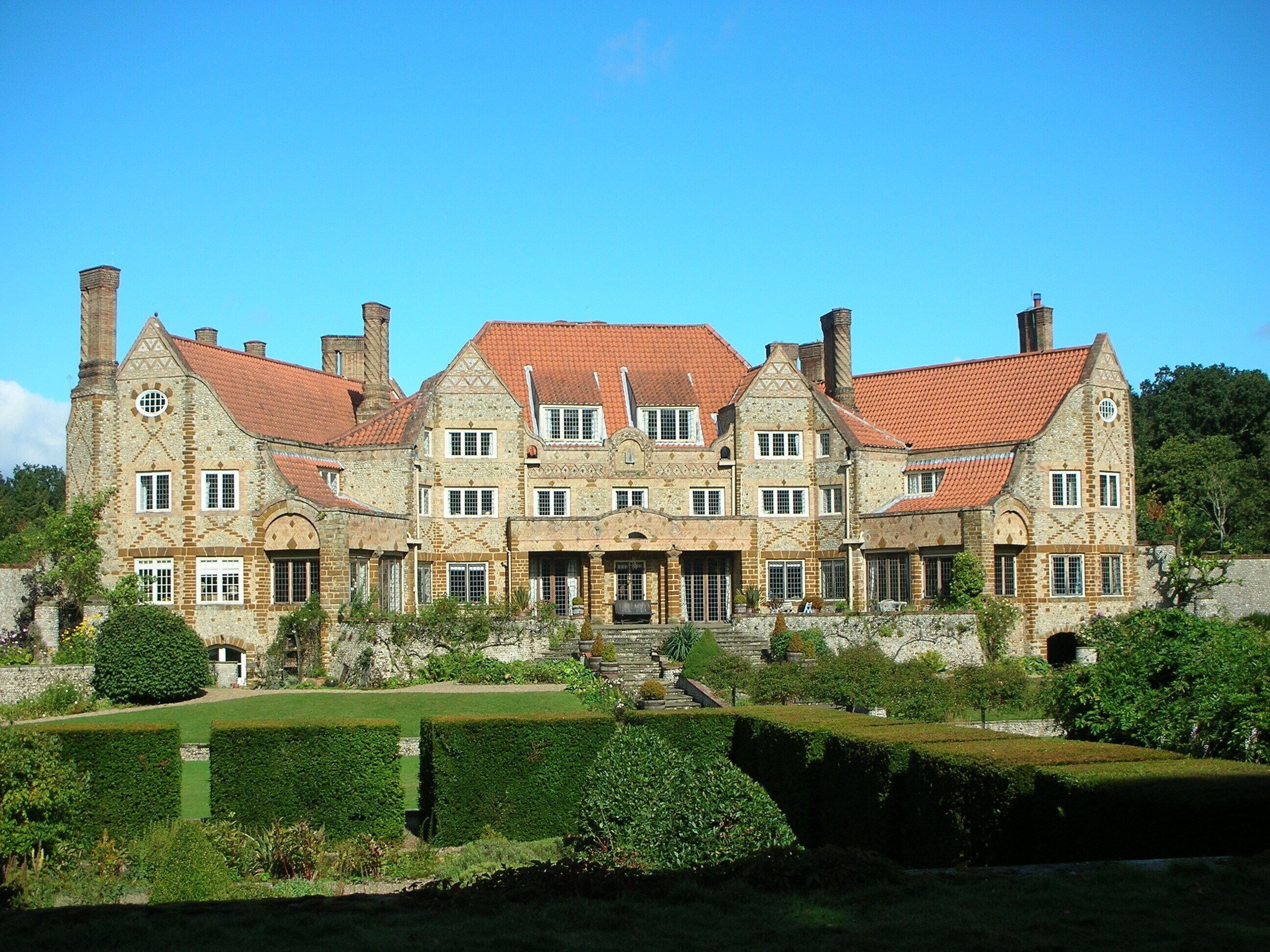 A large stone manor with a red-tiled roof and multiple chimneys.
