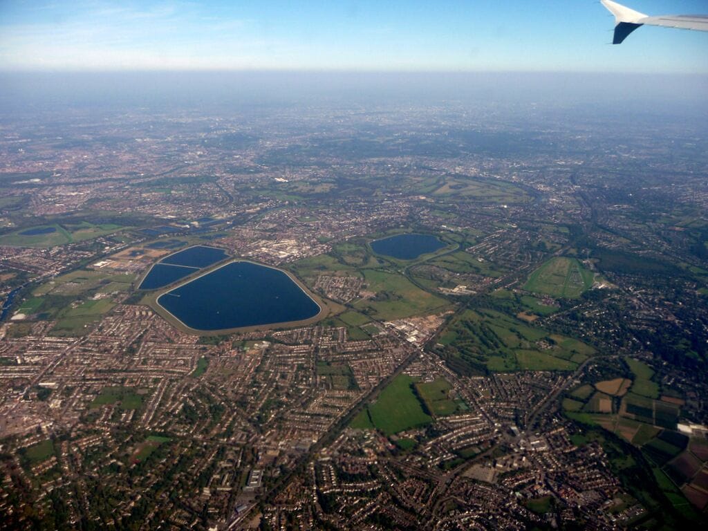 The east of Walton on Thames and Hersham is the foreground, due to perspective and background fog, the London Borough of Richmond Thames, largely consisting of parks makes up most of the rest of the image: features highlighted by hover-over boxes.