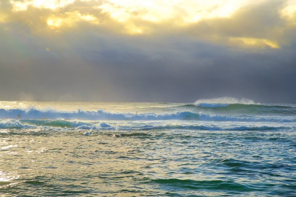 A coastal scene with waves and a cloudy sky.