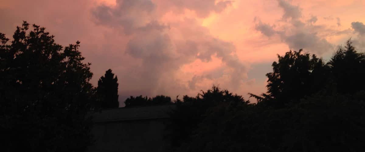 A sunset with clouds and silhouettes of trees.