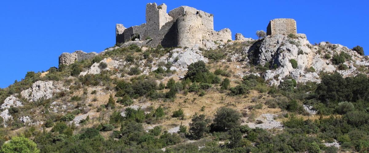 A medieval castle on a hill with rocky terrain and sparse vegetation.