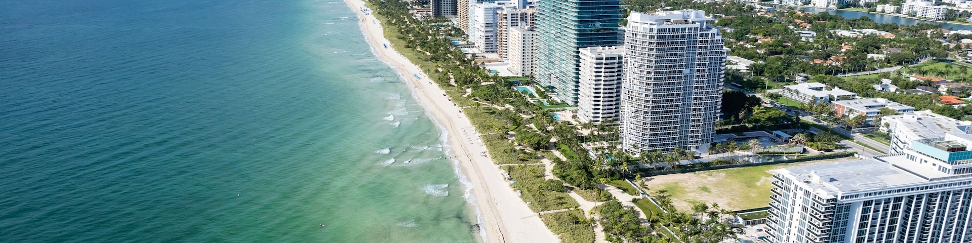 Paisagem costeira com praia, edifícios altos e uma linha de horizonte distante.