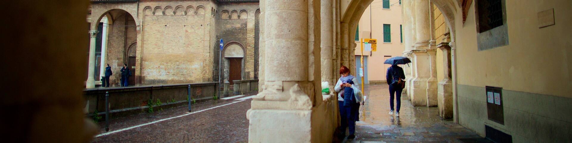 An arched corridor with a brick building in the background.
