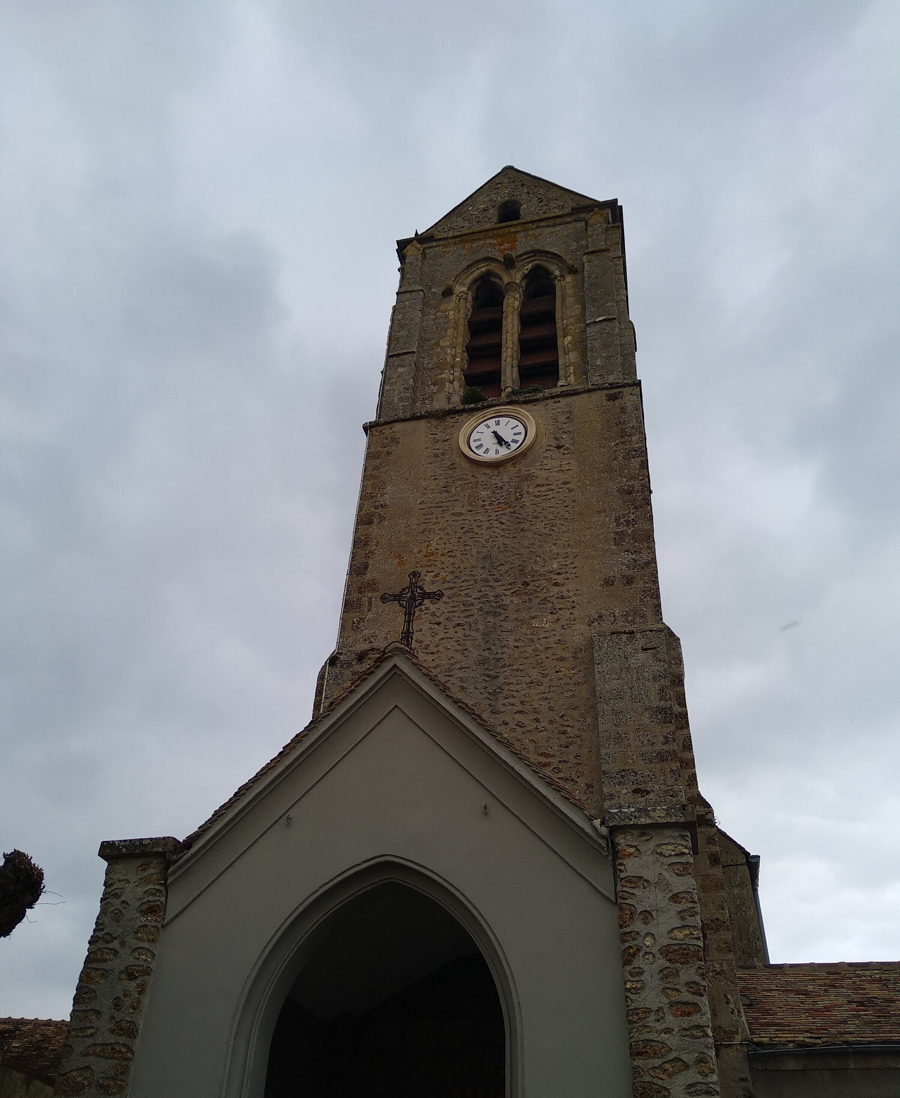 A church tower with a clock and a cross.