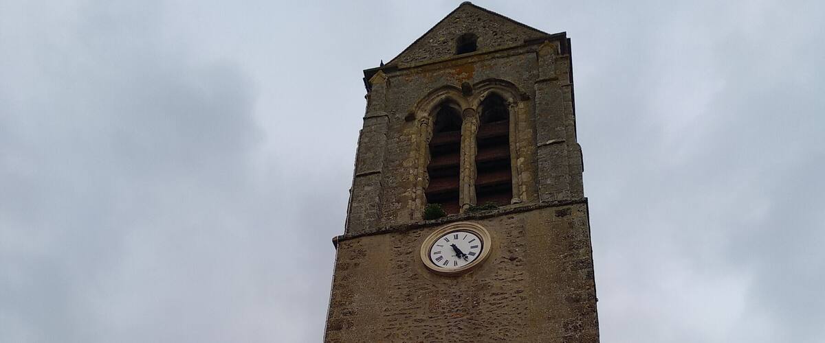 A church tower with a clock and a cross.