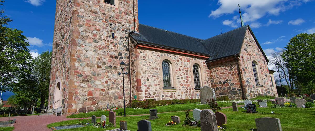 A stone church with a green roof and a steeple.