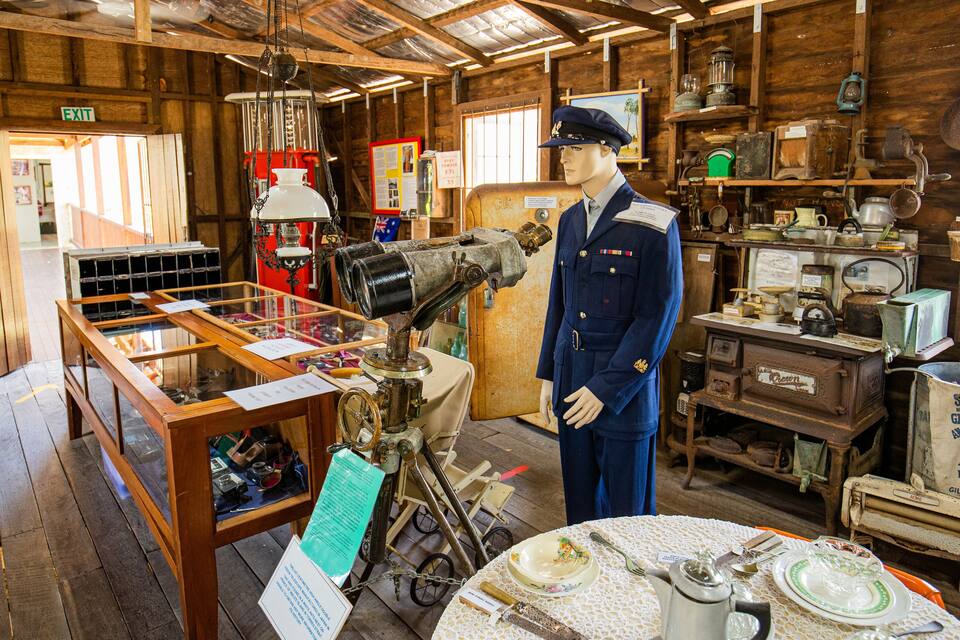 A historical exhibit with a mannequin, vintage equipment, and wooden interiors.