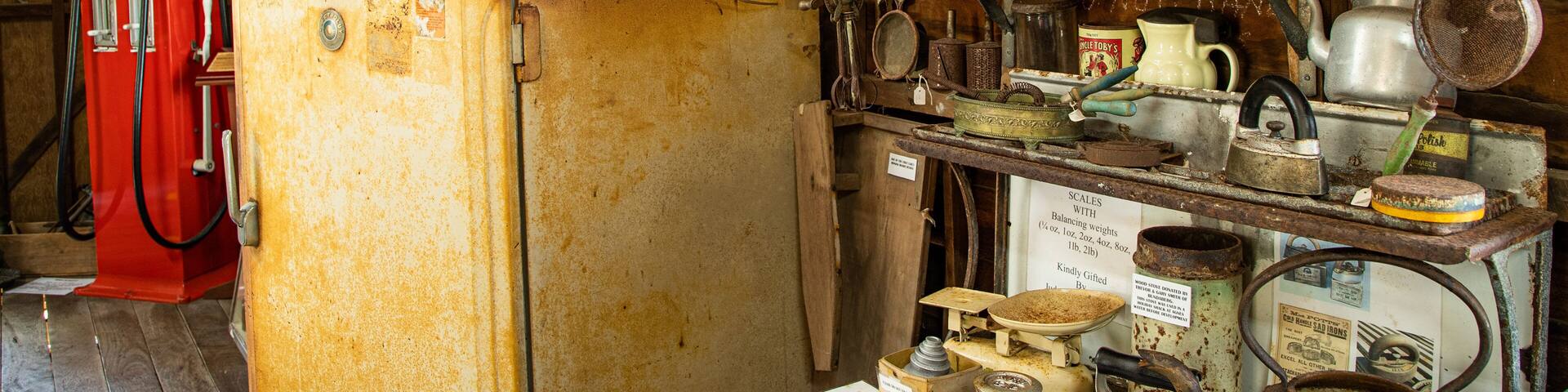 A rustic kitchen with vintage appliances, a red gas pump, and various old kitchen utensils.
