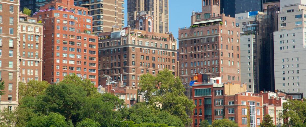 A cityscape with a mix of modern and historic buildings, including a prominent red brick building and a tall skyscraper.