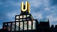 Un bâtiment surmonté d’un grand panneau lumineux en forme de « U » et doté de nombreuses fenêtres.