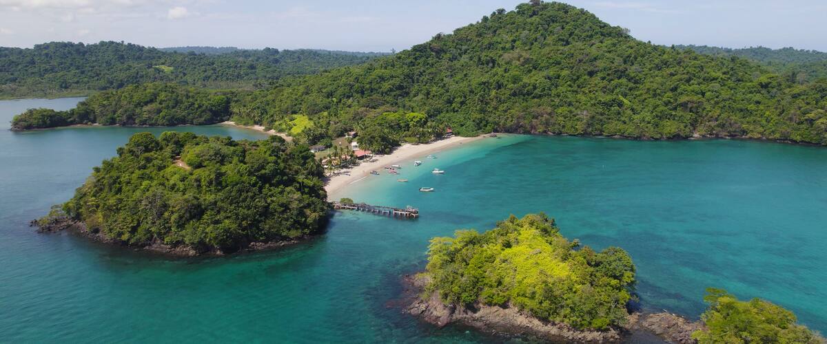 A tropical island with a beach, clear turquoise waters, and lush greenery.