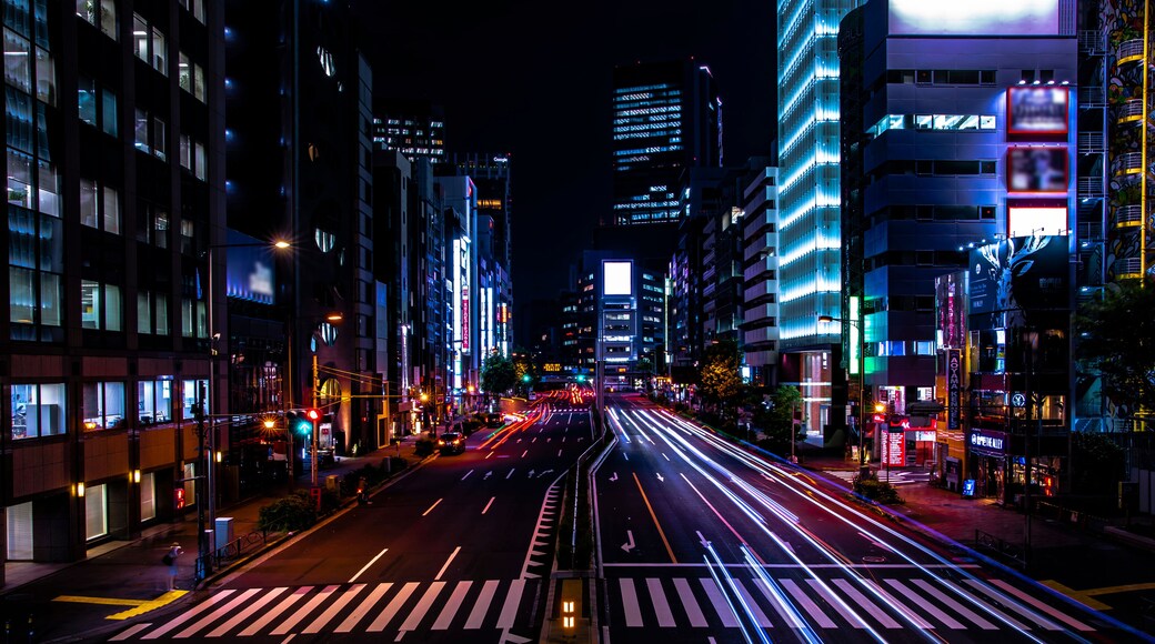 Une rue de la ville de nuit, avec des bâtiments illuminés et des traînées de lumière laissées par les véhicules en mouvement.