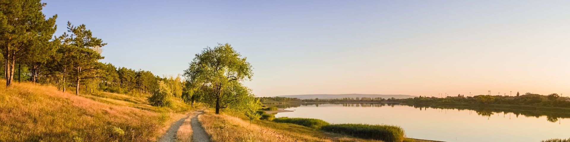 Scenic countryside landscape with rural dirt road across a meadow with dry grass and hay under a clear blue sky. Autumn panorama view near Delia lake, Ungheni, Moldova.