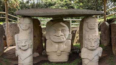 Une structure en pierre comportant trois faces sculptées sur des piliers, chacun supportant une pierre plate sur le dessus.