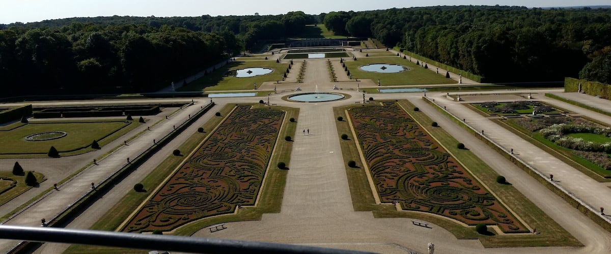 A formal garden with symmetrical pathways, fountains, and manicured lawns.