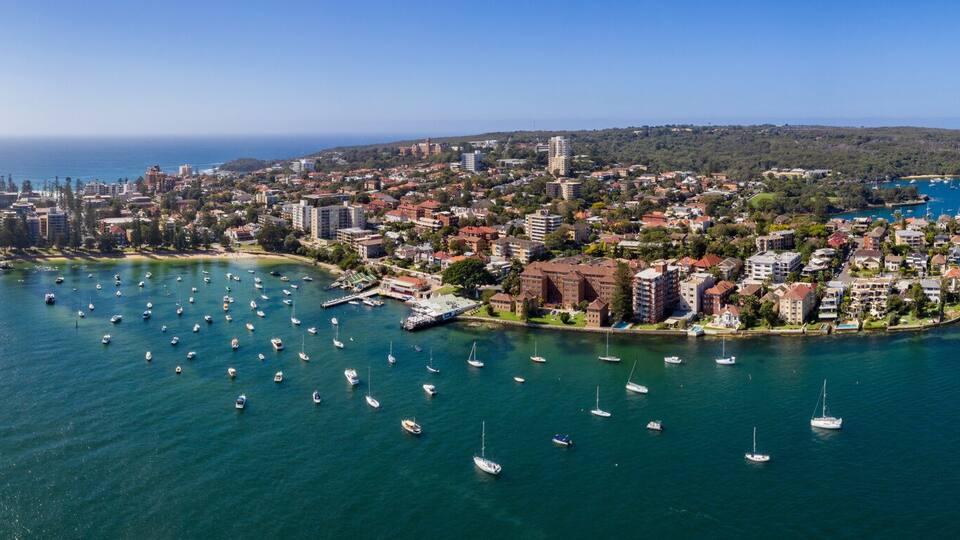 A coastal cityscape with a marina, boats, and buildings along the waterfront.
