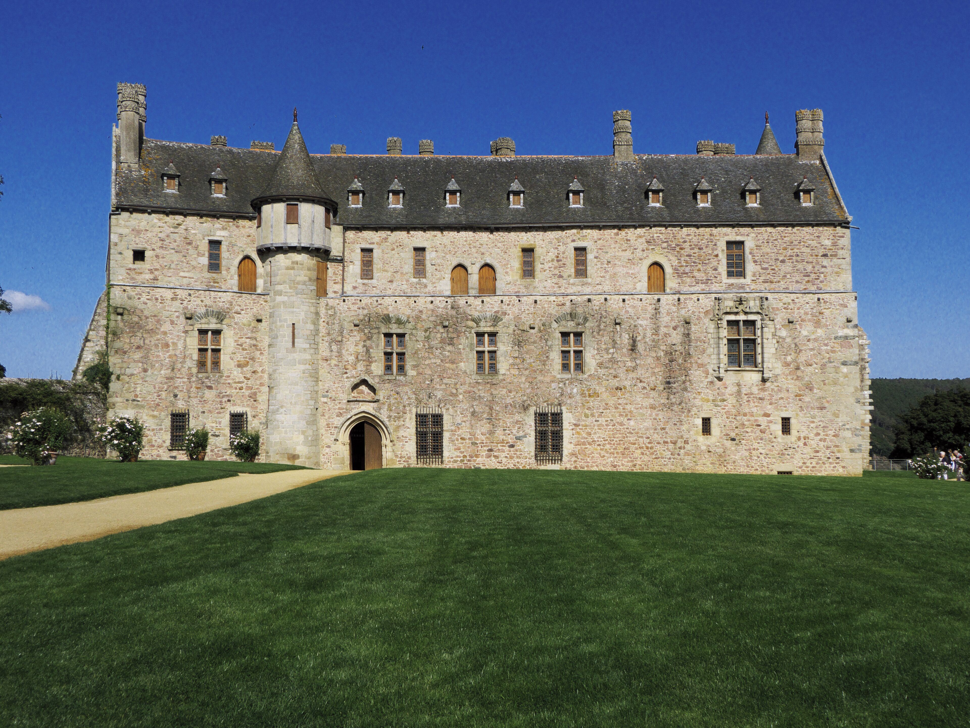 A large stone castle with a central tower, surrounded by a well-maintained lawn.