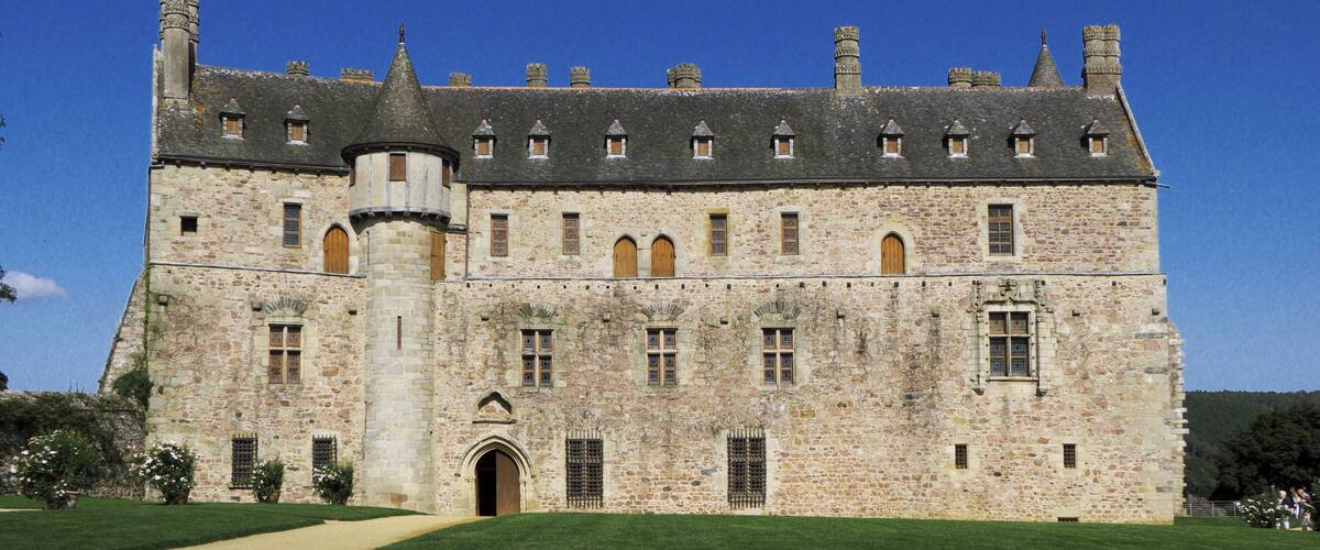 A large stone castle with a central tower, surrounded by a well-maintained lawn.