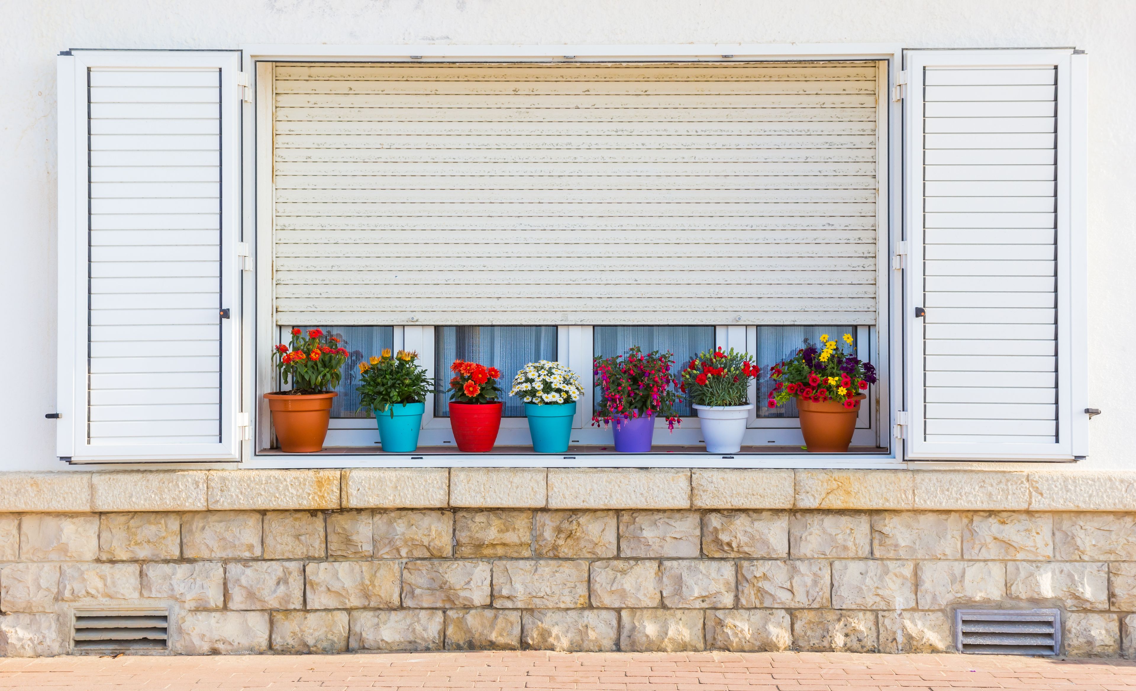 Colorful pots with plants in the windowsill of a typical Spanish home