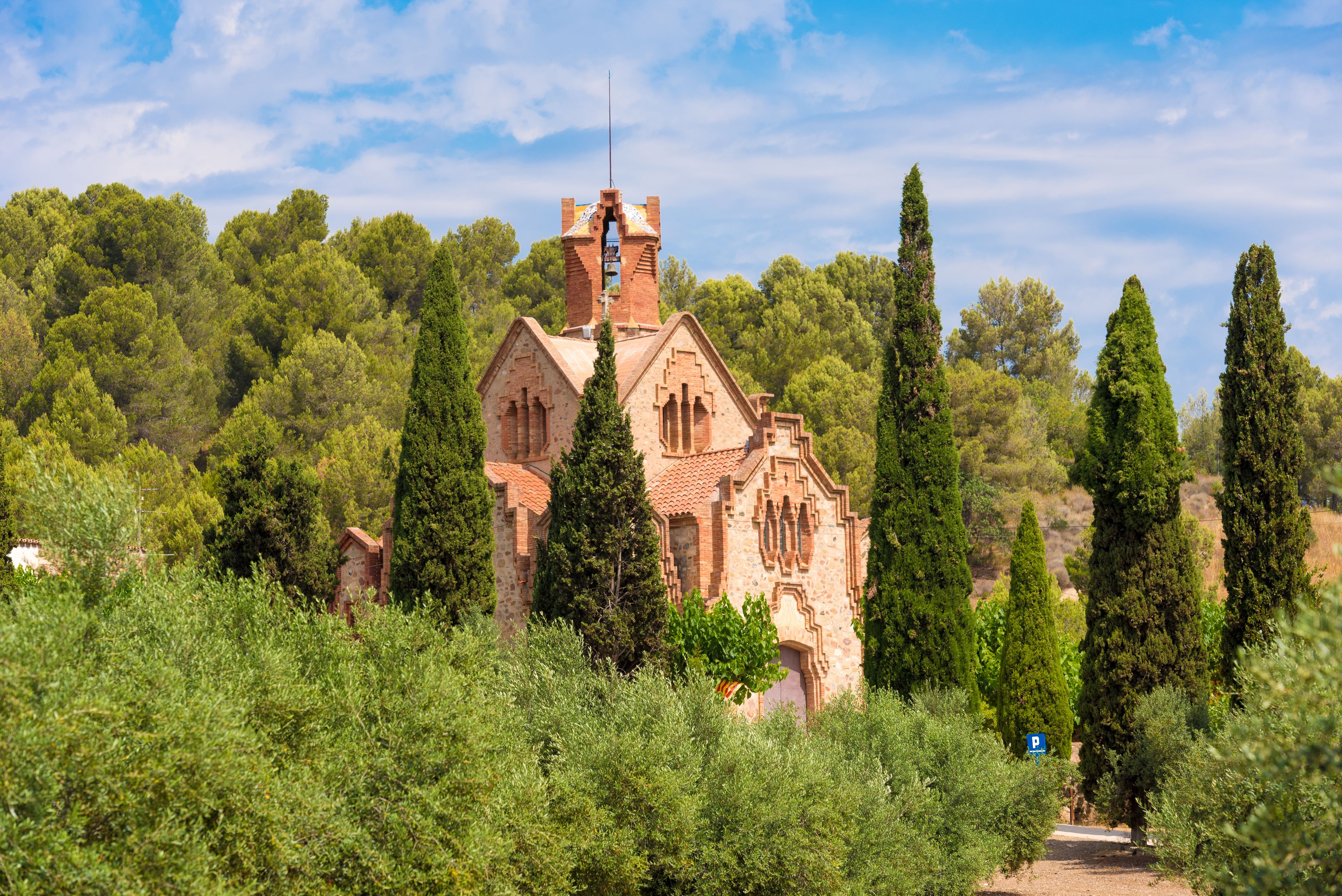 Eine historische Kirche, umgeben von üppiger Vegetation und hoch aufragenden Zypressen.