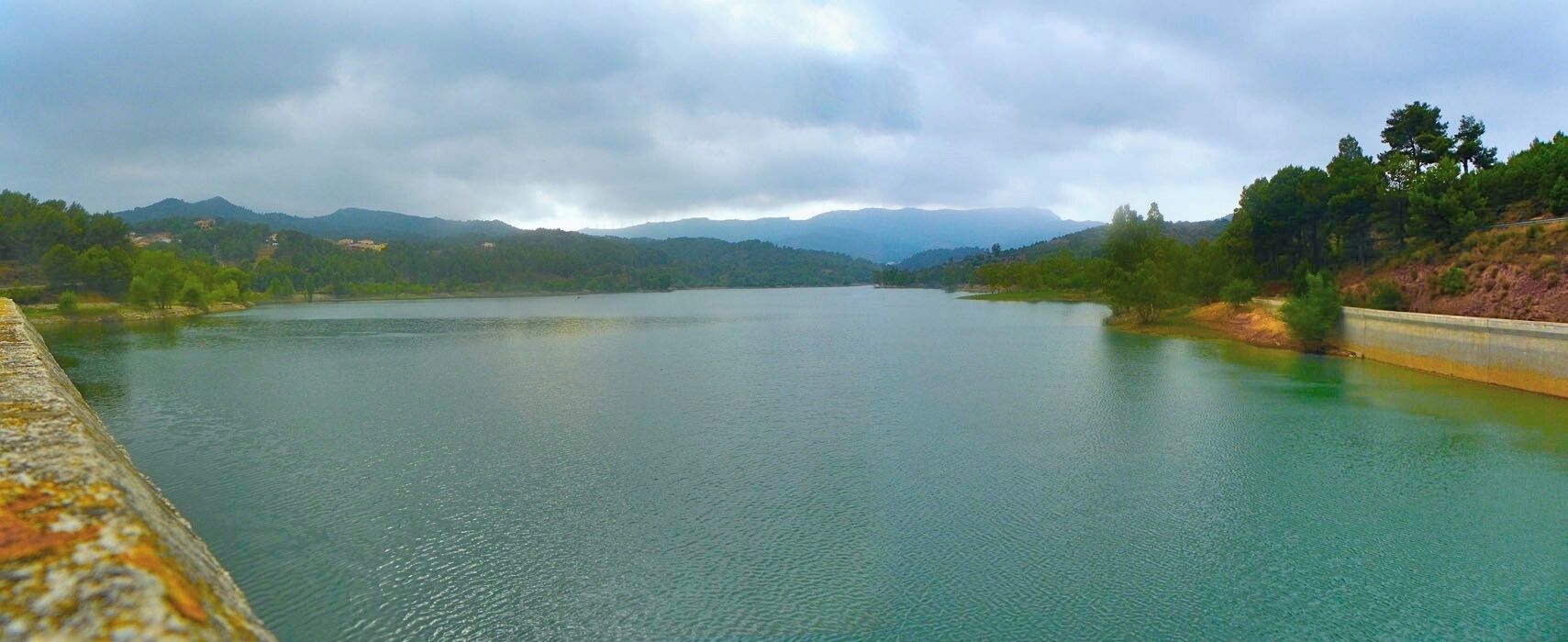 A calm lake surrounded by hills and trees.